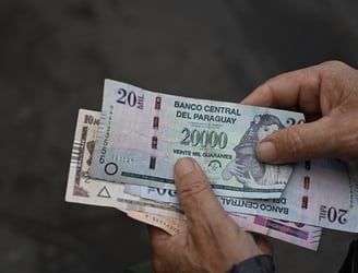 A diferencia de otras monedas el mundo, el guaraní conserva sus ceros. (Photo by Luis ROBAYO / AFP)