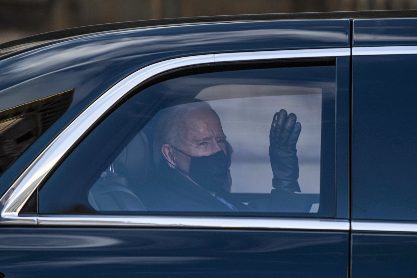 US President Joe Biden waves to supporters along the motorcade route in Washington, DC, January 20,2021after being sworn in as the 46th President of the United States. (Photo by SETH HERALD / AFP)