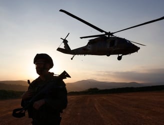 Un soldado israelí mira el horizonte mientras un helicóptero despega. (Photo by Jalaa MAREY / AFP)