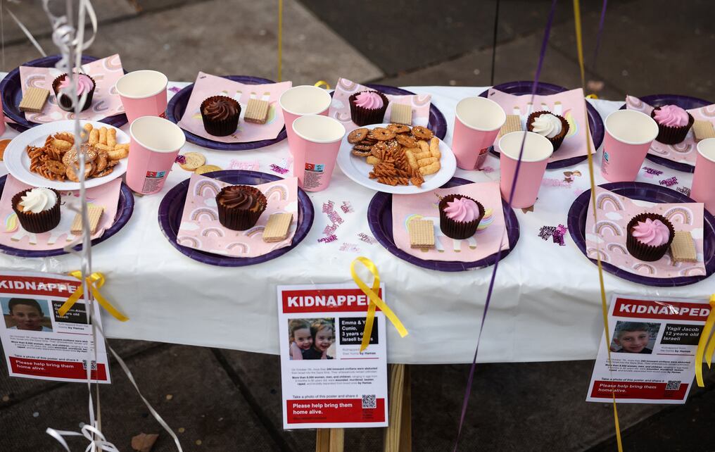 Carteles que muestran a niños tomados como rehenes por Hamás en una mesa decorada frente a la oficina de la ONG Save The Children. Foto: AFP