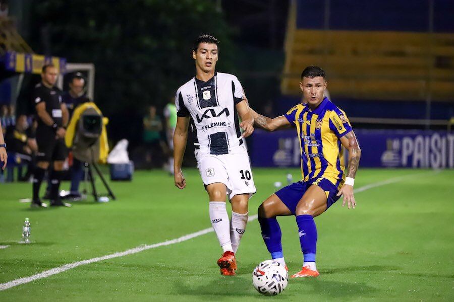 Derlis Rodríguez, gran figura de Tacuary, disputa la posesión del balón con el luqueño Rodi Ferreira. Foto: APF