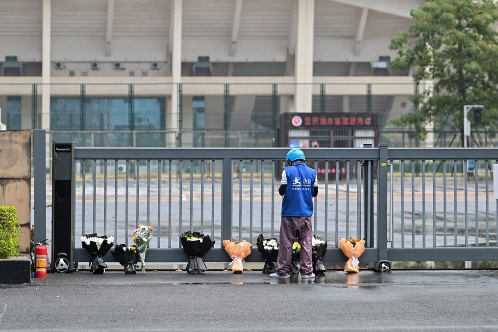 Un repartidor coloca pedidos online de ramos de flores en un monumento improvisado fuera del Centro Deportivo Zhuhai. Foto: Héctor Retamal/AFP