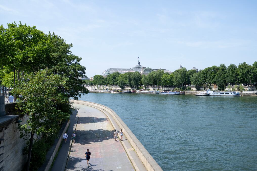 La gente camina por las orillas del río Sena durante una tarde cálida con el Grand Palais al fondo, en París. Foto: Emma Da Silva/AFP