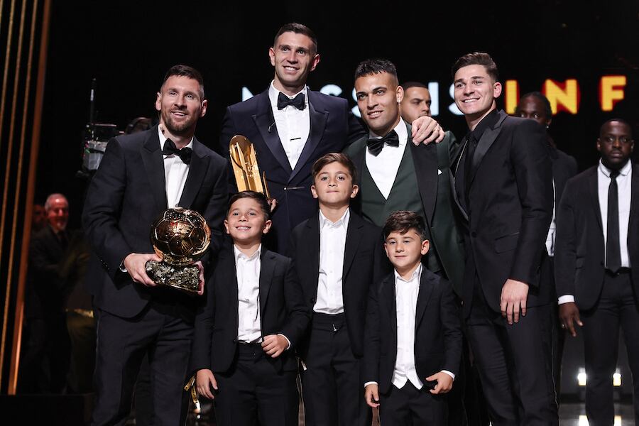 El premiado Lionel Messi sostiene su trofeo junto a sus hijos, el portero Emiliano Martínez, los delanteros Lautaro Martínez y Julián Álvarez, todos argentinos, durante la gala de premiación.FOTO:AFP
