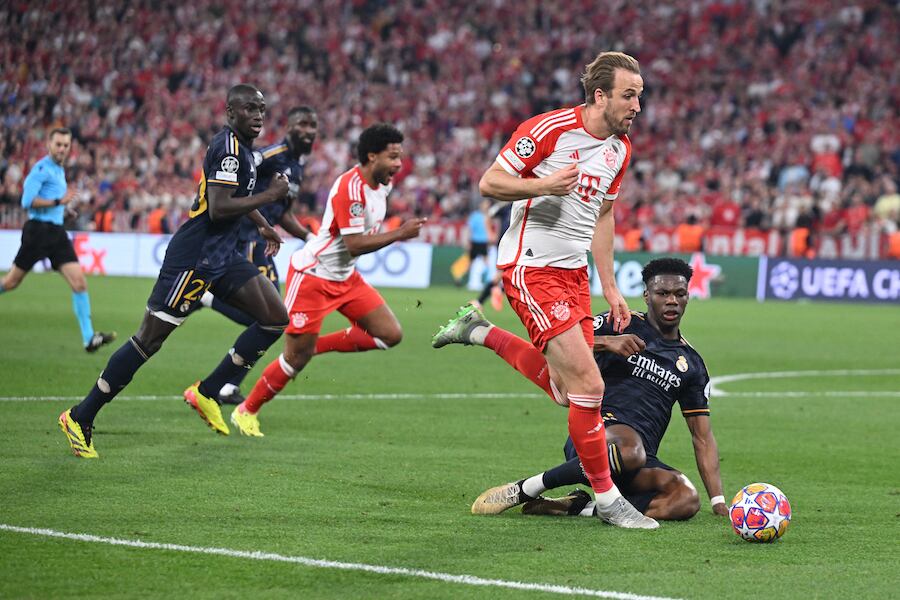El delantero Harry Kane del Bayern intenta superar al defensor de Real Aurelien Tchouameni en el duelo semifinal de ayer por la Liga de Campeones.FOTO: AFP
