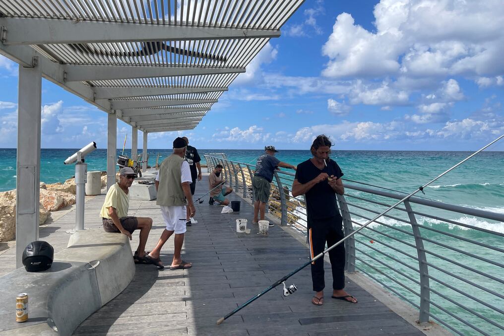 La gente pesca a lo largo de un embarcadero en la ciudad costera israelí de Nahariya, cerca de la frontera con el Líbano. Foto: AFP