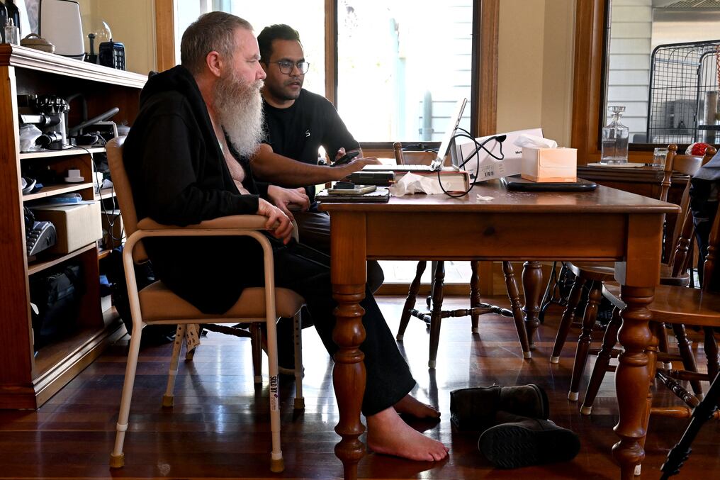 Rodney Gorham (izquierda) es receptor de un implante cerebral Synchron, trabajando en una computadora en su casa en Melbourne con el ingeniero Zafar Faraz. Foto: AFP