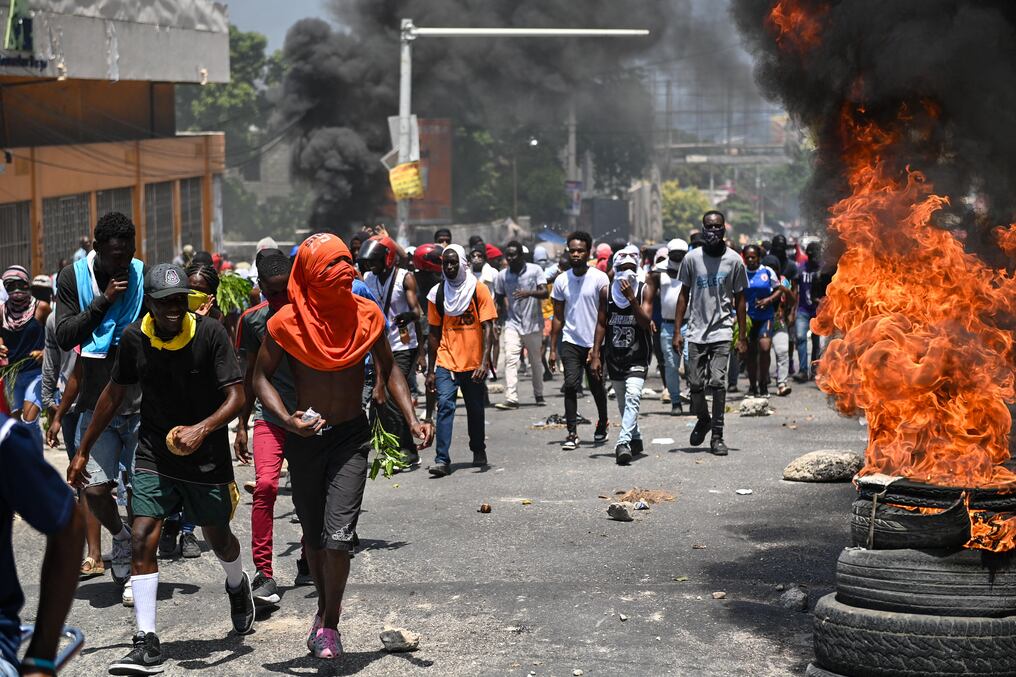 La gente marcha mientras se queman los neumáticos durante una protesta contra la inseguridad en Puerto Príncipe. Foto: AFP