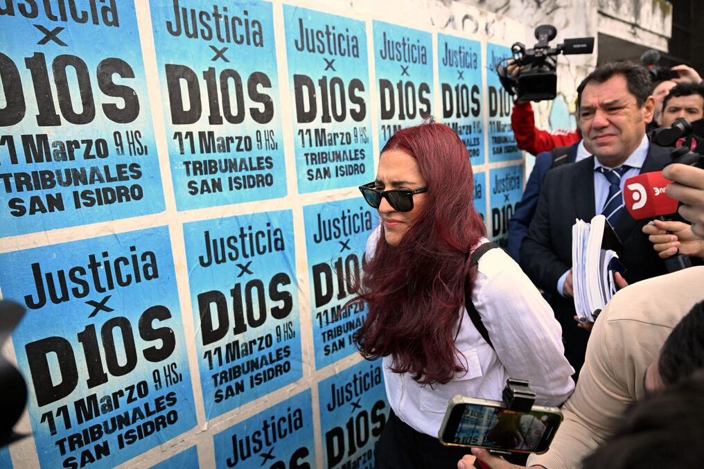 Jana Maradona, hija del fallecido futbolista, pasa junto a carteles a su llegada al juzgado de San Isidro. Foto: Luis Robayo/AFP