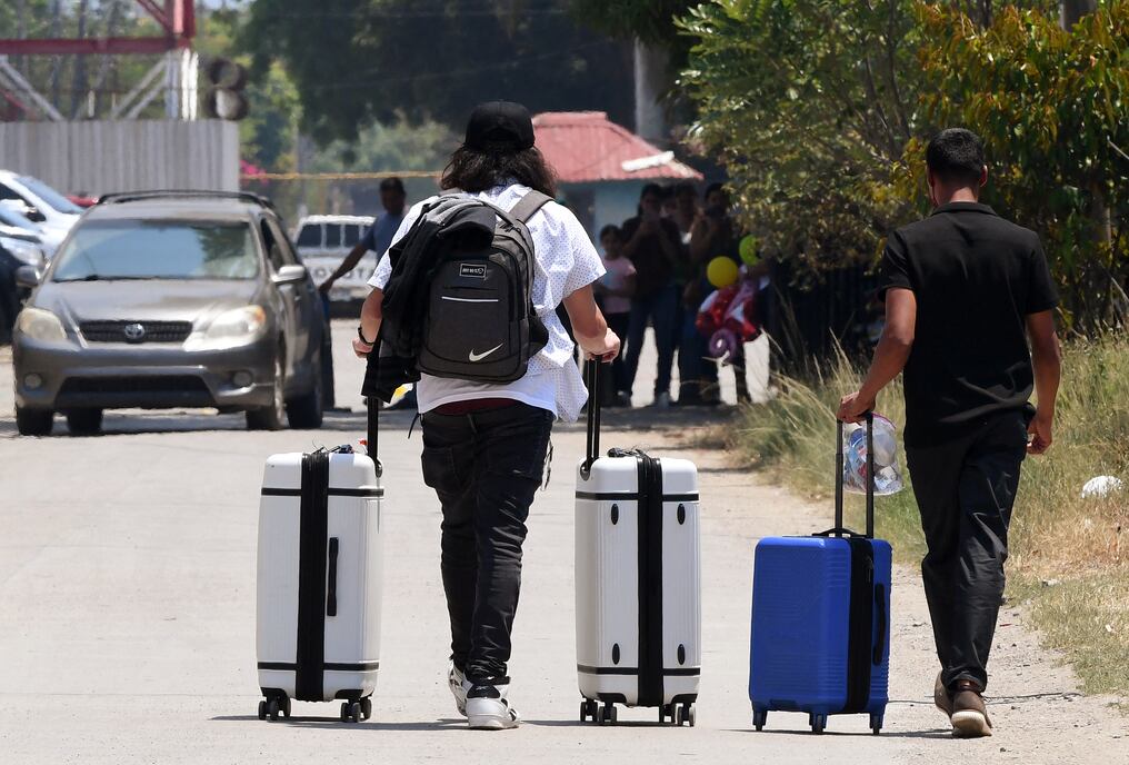 Hombres salen del aeropuerto Ramón Villeda Morales, adonde llegaron autodeportados desde Estados Unidos. Foto: Orlando Sierra/AFP
