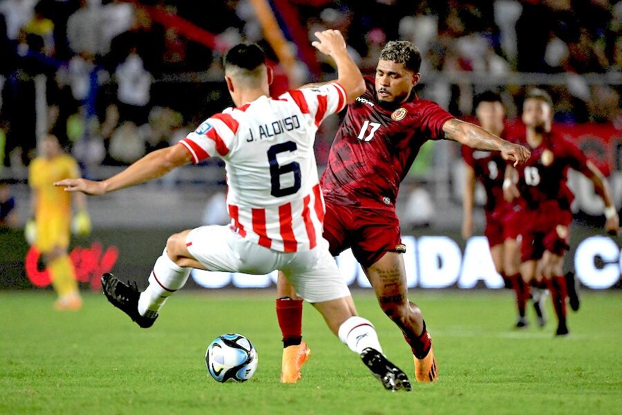 El lateral izquierdo albirrojo Júnior Alonso se cruza en el camino del venezolano Josef Martínez.FOTO:AFP