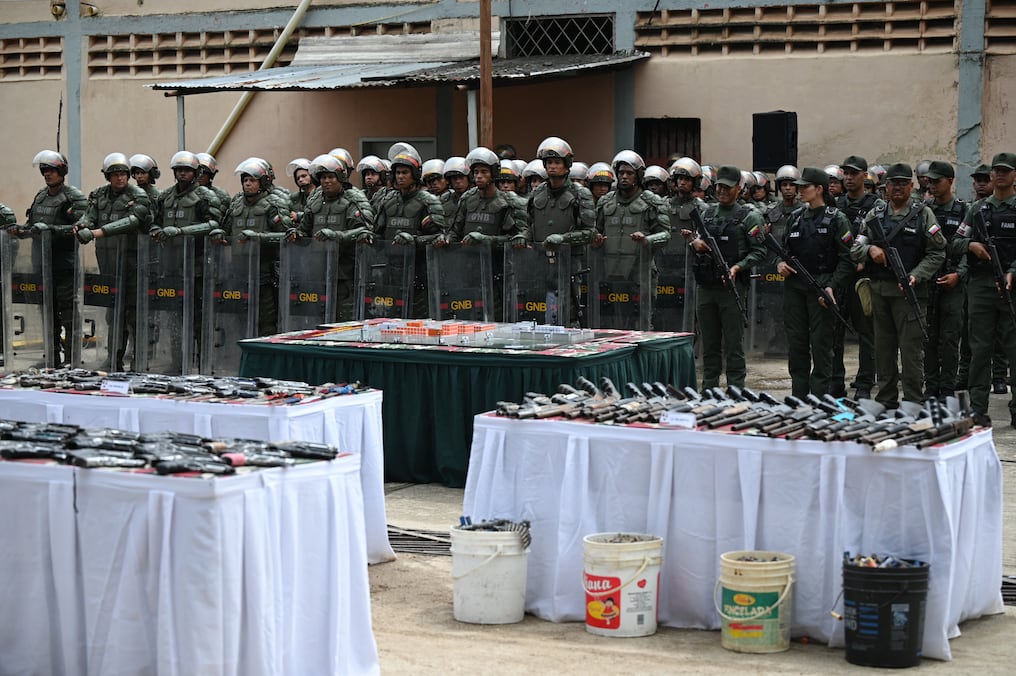Miembros de la Guardia Nacional Bolivariana (GNB) hacen guardia mientras se exhiben armas y municiones confiscadas en la prisión de Tocuyito. Foto: AFP