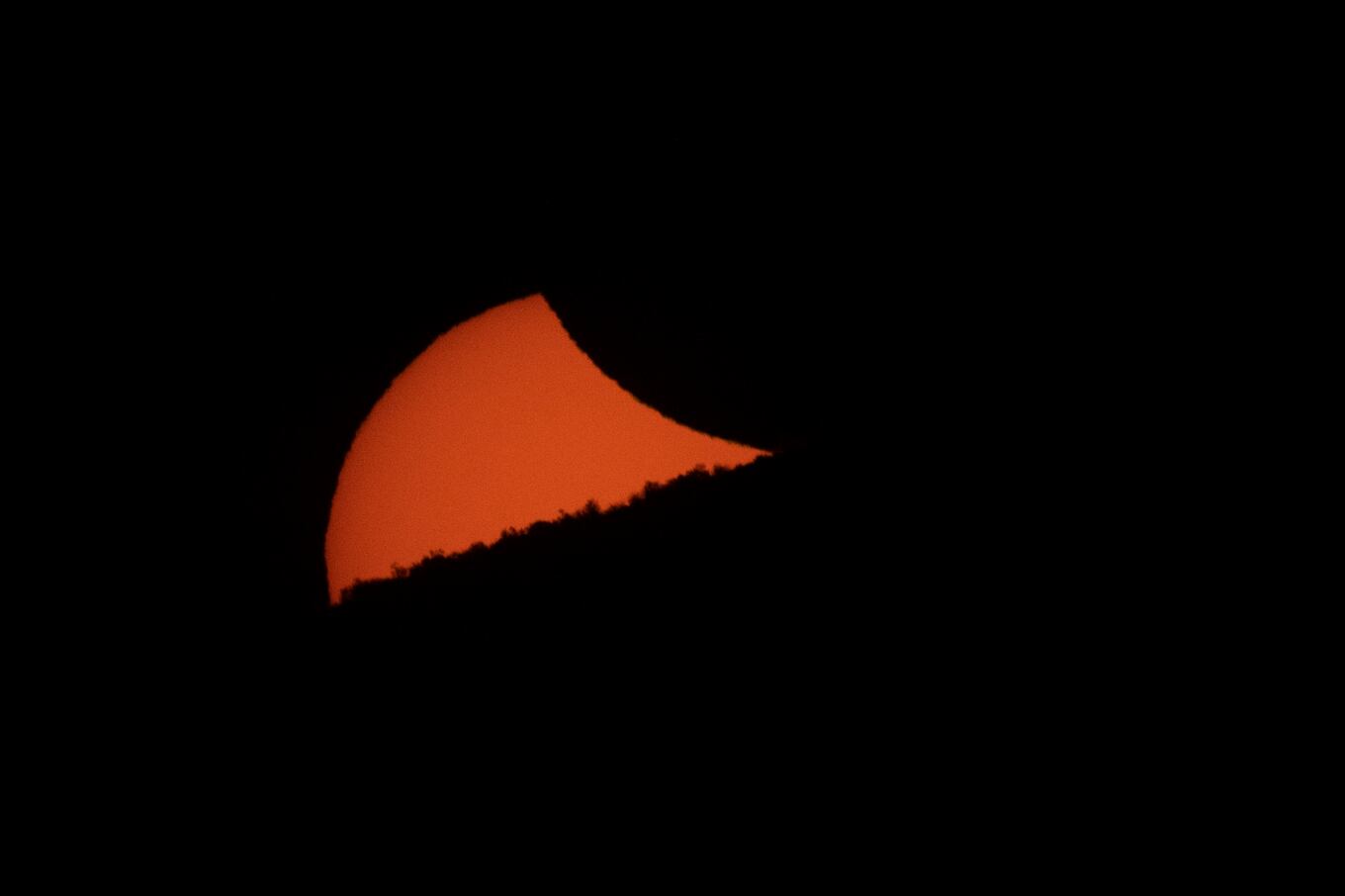 A partially eclipsed sun sets behind a mountain ridge as seen from El Molle, Chile, on July 2, 2019 after the total solar eclipse. - Tens of thousands of tourists braced Tuesday for a rare total solar eclipse that was expected to turn day into night along a large swath of Latin America's southern cone, including much of Chile and Argentina. (Photo by Stan HONDA / AFP)
