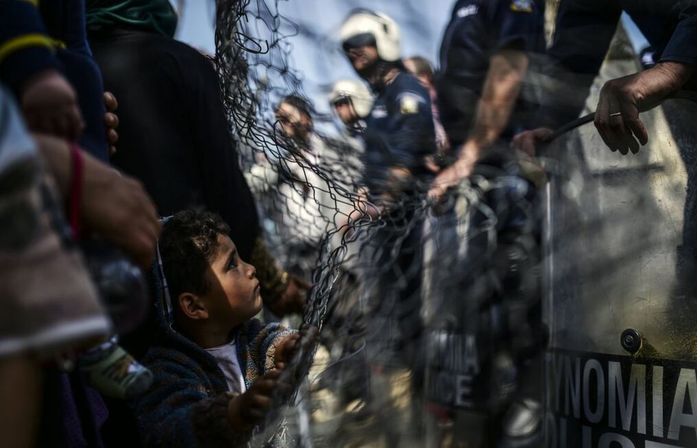 Policías bloquean una protesta de migrantes, en un refugio ubicado en la frontera de Grecia con Macedonia. Este niño mira sin comprender.