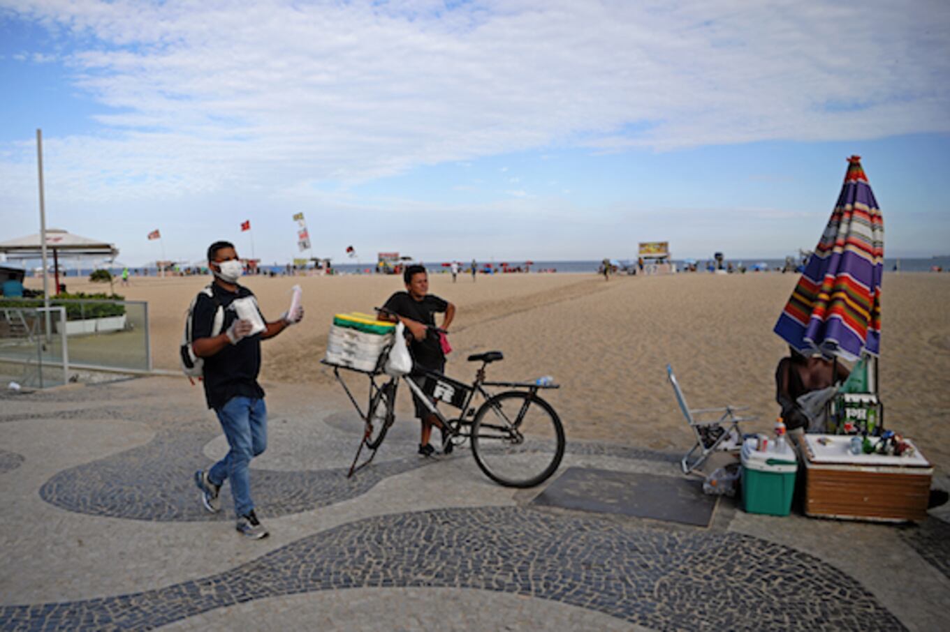 Un vendedor ambulante vende máscaras faciales como medida preventiva contra la propagación del nuevo coronavirus en la playa de Copacabana en Río de Janeiro, una de las más famosas del mundo, donde los socorristas pedían a los bañistas que evitaran congregarse en grandes cantidades.FOTO:AFP