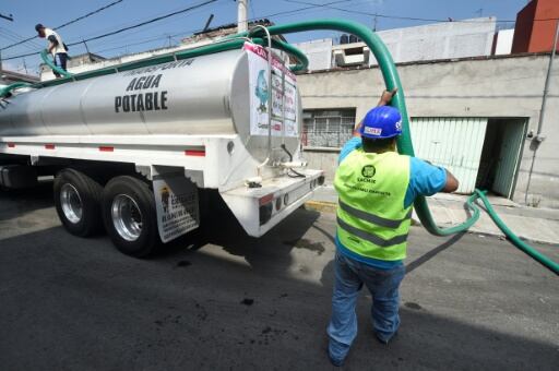Un empleado del Sistema de Agua de Ciudad de México distribuye agua potable con un tanque.
