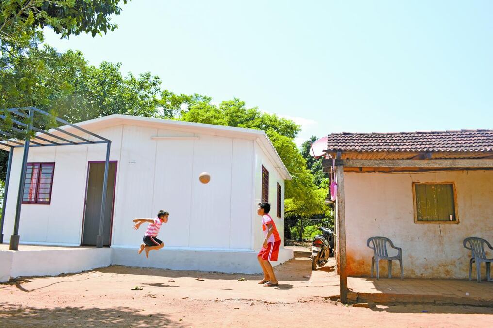Los niños juegan felices junto a su nuevo hogar.[/caption]