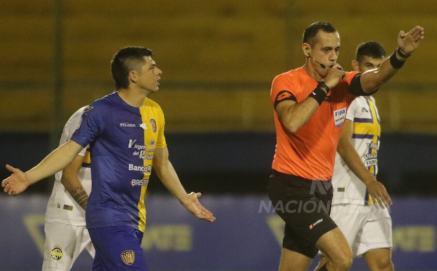 El árbitro Juan Benítez cobró un dudoso penal para Trinidense y el
capitán de Luqueño Rodrigo Rojas reclama al juez.FOTO:NÉSTOR SOTO