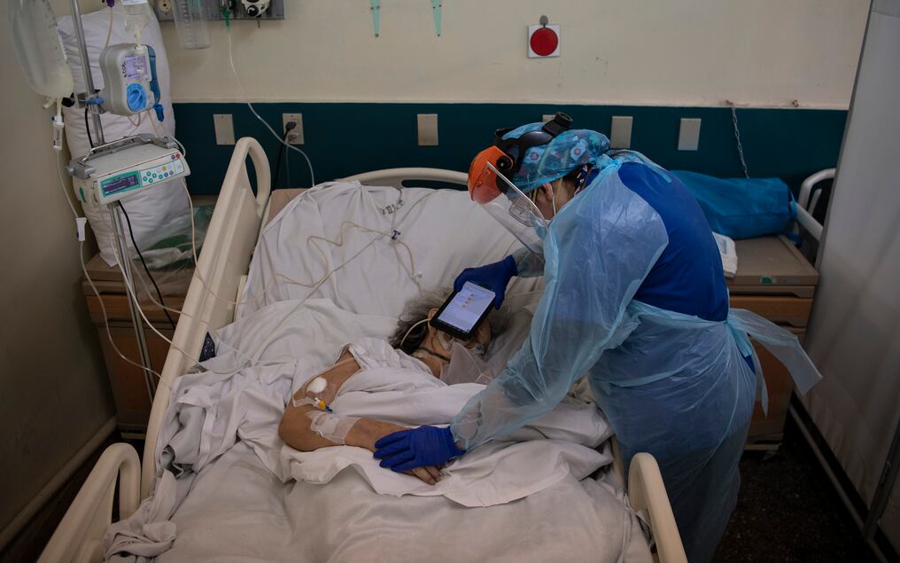 El doctor Moyra López sostiene una tableta para que un paciente terminal escuche un mensaje de despedida de sus familiares. Foto: AFP.