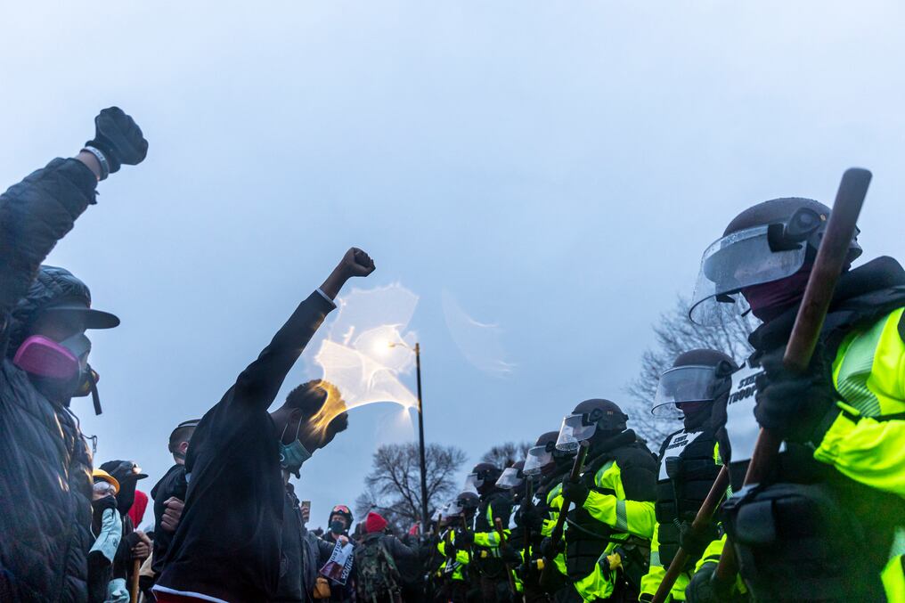La gente levanta los puños y se enfrenta a una fila de policías estatales al comienzo del toque de queda para protestar por la muerte de Daunte Wright.  Foto: AFP.