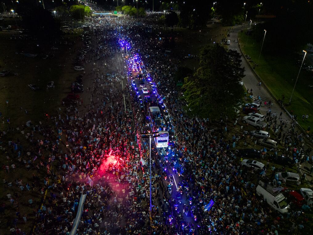 Pese a la hora, una multitud se congregó al borde de la carretera y dificultó el avance del autobús, que tardó una hora y cuarto en recorrer los 11 kilómetros entre el aeropuerto y el predio de la AFA. Foto: AFP.