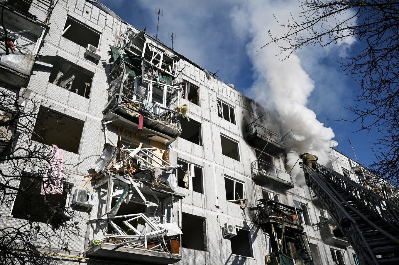 Firefighters work on a fire on a building after bombings on the eastern Ukraine town of Chuguiv on February 24, 2022, as Russian armed forces are trying to invade Ukraine from several directions, using rocket systems and helicopters to attack Ukrainian position in the south, the border guard service said. - Russia's ground forces today crossed into Ukraine from several directions, Ukraine's border guard service said, hours after President Vladimir Putin announced the launch of a major offensive. Russian tanks and other heavy equipment crossed the frontier in several northern regions, as well as from the Kremlin-annexed peninsula of Crimea in the south, the agency said. (Photo by Aris Messinis / AFP)