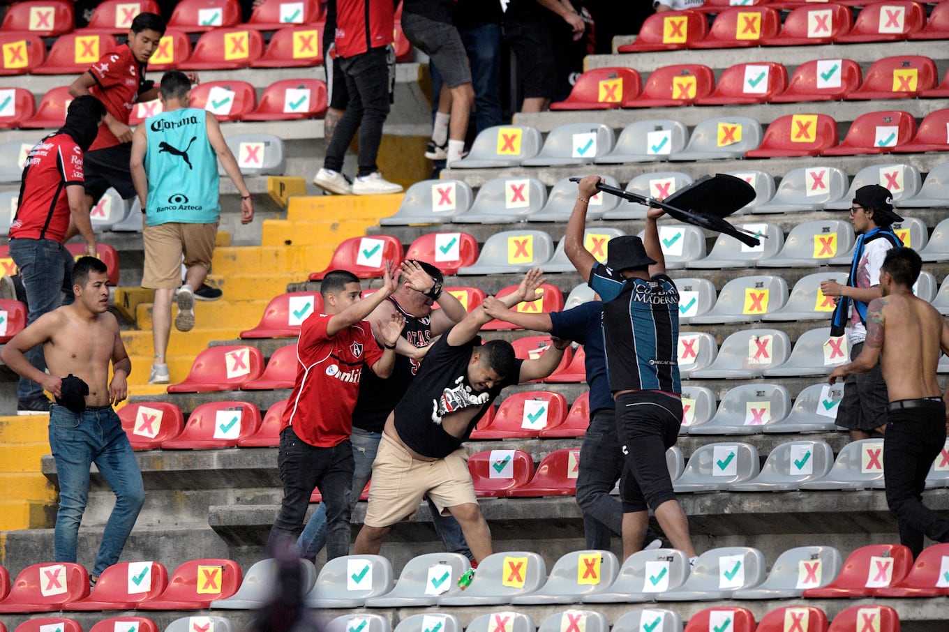 Supporters of Atlas fight with supporters of Queretaro during the Mexican Clausura tournament football match between Queretaro and Atlas at Corregidora stadium in Queretaro, Mexico on March 5, 2022. - A match between Mexican football clubs was called off March 5, 2022 after violence by opposing fans spilled onto the field. The game between Queretaro and Atlas at La Corregidora stadium in the city of Queretaro -- the ninth round of the 2022 Clausura football tournament -- was in its 63rd minute when fights between opposing fans broke out. (Photo by AFP)