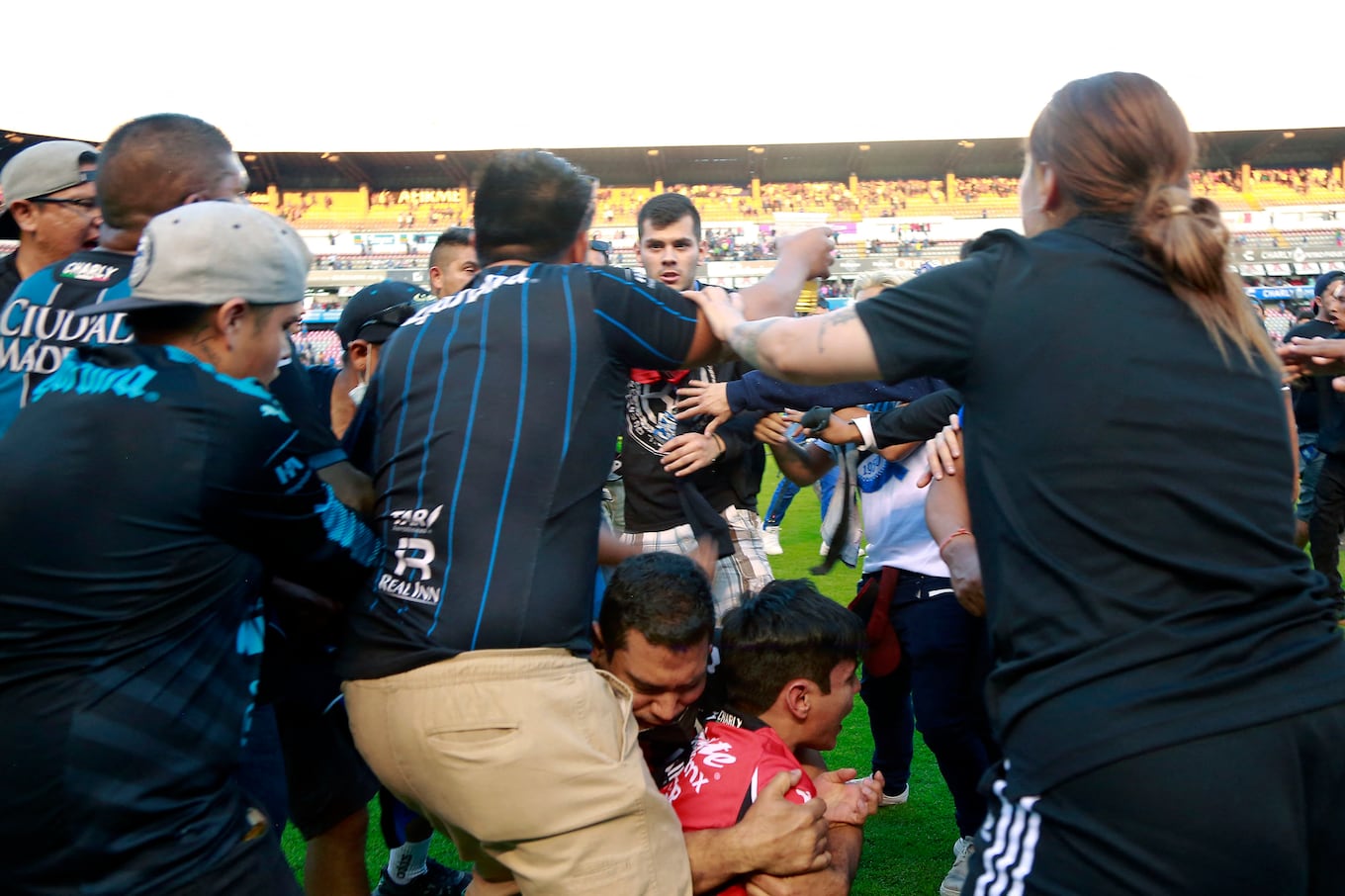Supporters of Atlas fight with supporters of Queretaro during the Mexican Clausura tournament football match between Queretaro and Atlas at Corregidora stadium in Queretaro, Mexico on March 5, 2022. - A match between Mexican football clubs was called off March 5, 2022 after violence by opposing fans spilled onto the field. The game between Queretaro and Atlas at La Corregidora stadium in the city of Queretaro -- the ninth round of the 2022 Clausura football tournament -- was in its 63rd minute when fights between opposing fans broke out. (Photo by EDUARDO GOMEZ / AFP)