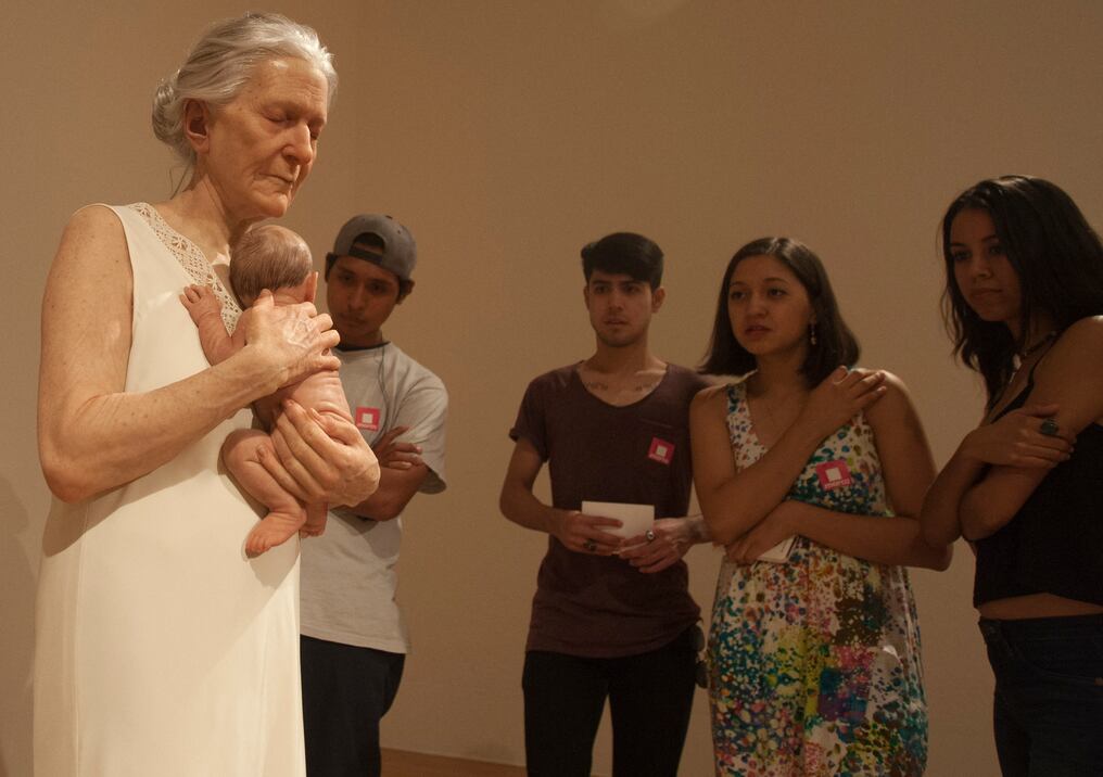 La gente mira la escultura hiperrealista “La abuela” del artista australiano Ron Mueck. Foto: AFP.