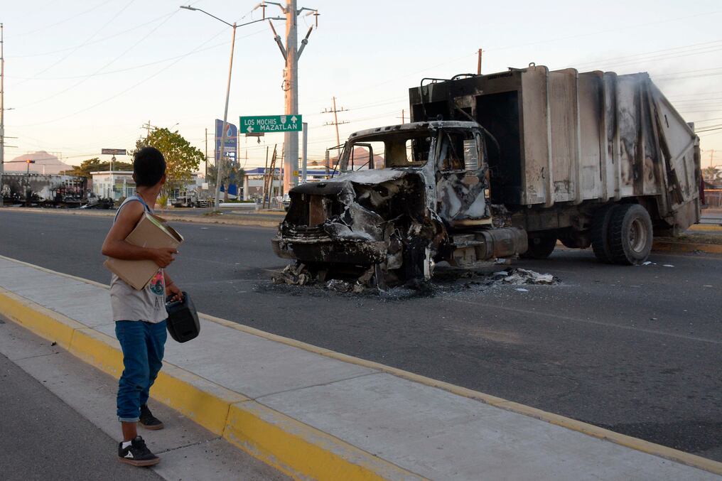 Un hombre pasa junto a un camión quemado en una calle de Culiacán, en el estado de Sinaloa. Foto: AFP.