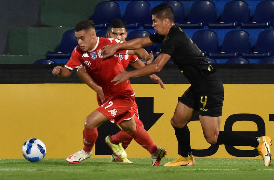 Elías Alfonso de General Caballero se escapa de Kendrys Silva de La Guaira venezo­lano en la jornada de fútbol de anoche en el Defen­sores del Chaco. FOTO:AFP