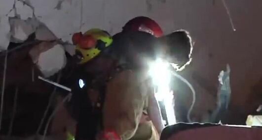 El menor fue sacado de entre los escombros cuando se desarrollaban las labores de remoción. Foto: captura de vídeo.