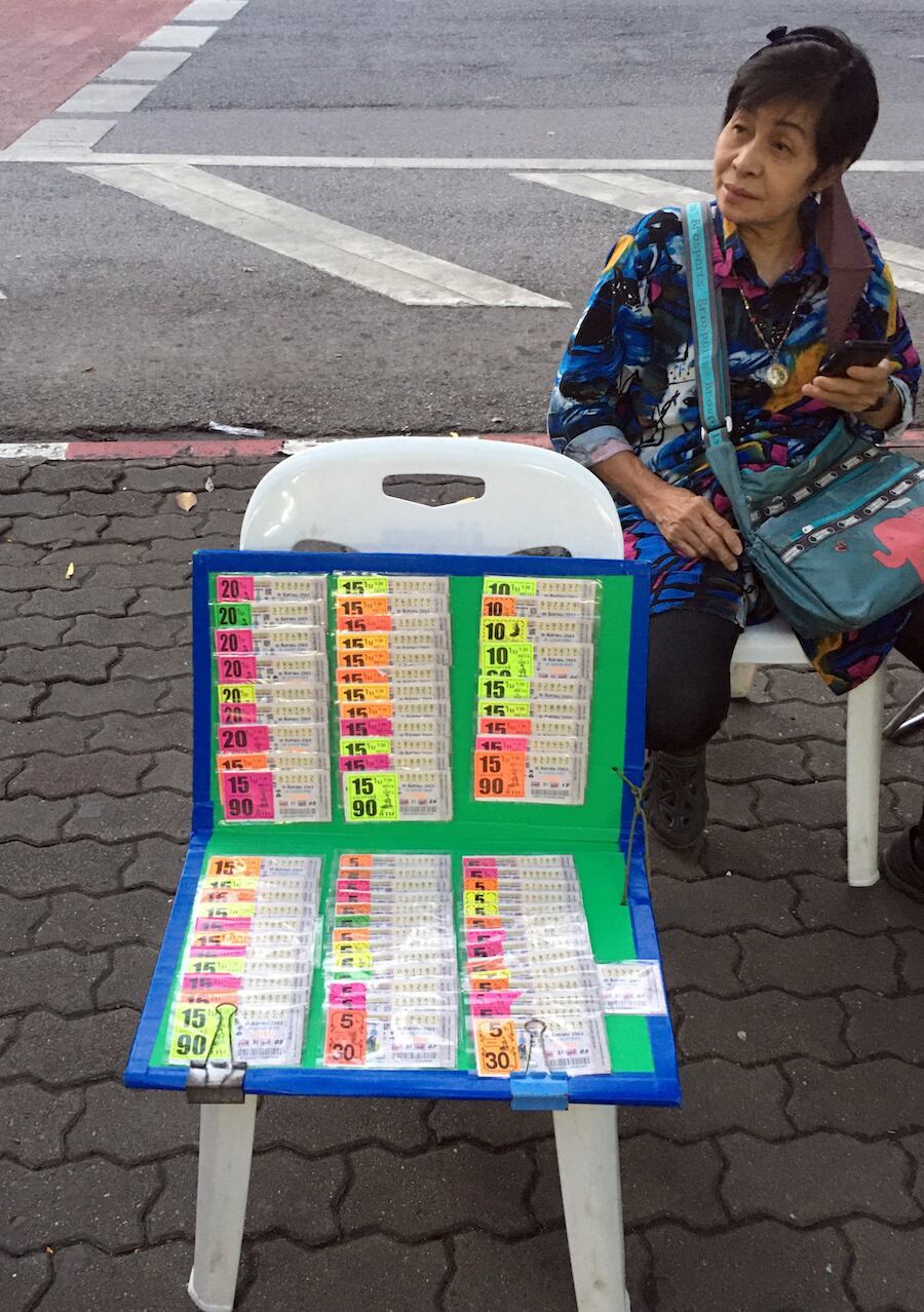 Una mujer vende billetes de lotería frente al costado de una ruta en Tailandia. La lotería estatal es el único juego de azar permitido en el país.