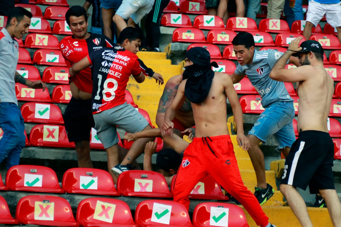 Supporters of Atlas fight with supporters of Queretaro during the Mexican Clausura tournament football match between Queretaro and Atlas at Corregidora stadium in Queretaro, Mexico on March 5, 2022. - A match between Mexican football clubs was called off March 5, 2022 after violence by opposing fans spilled onto the field. The game between Queretaro and Atlas at La Corregidora stadium in the city of Queretaro -- the ninth round of the 2022 Clausura football tournament -- was in its 63rd minute when fights between opposing fans broke out. (Photo by EDUARDO GOMEZ / AFP)