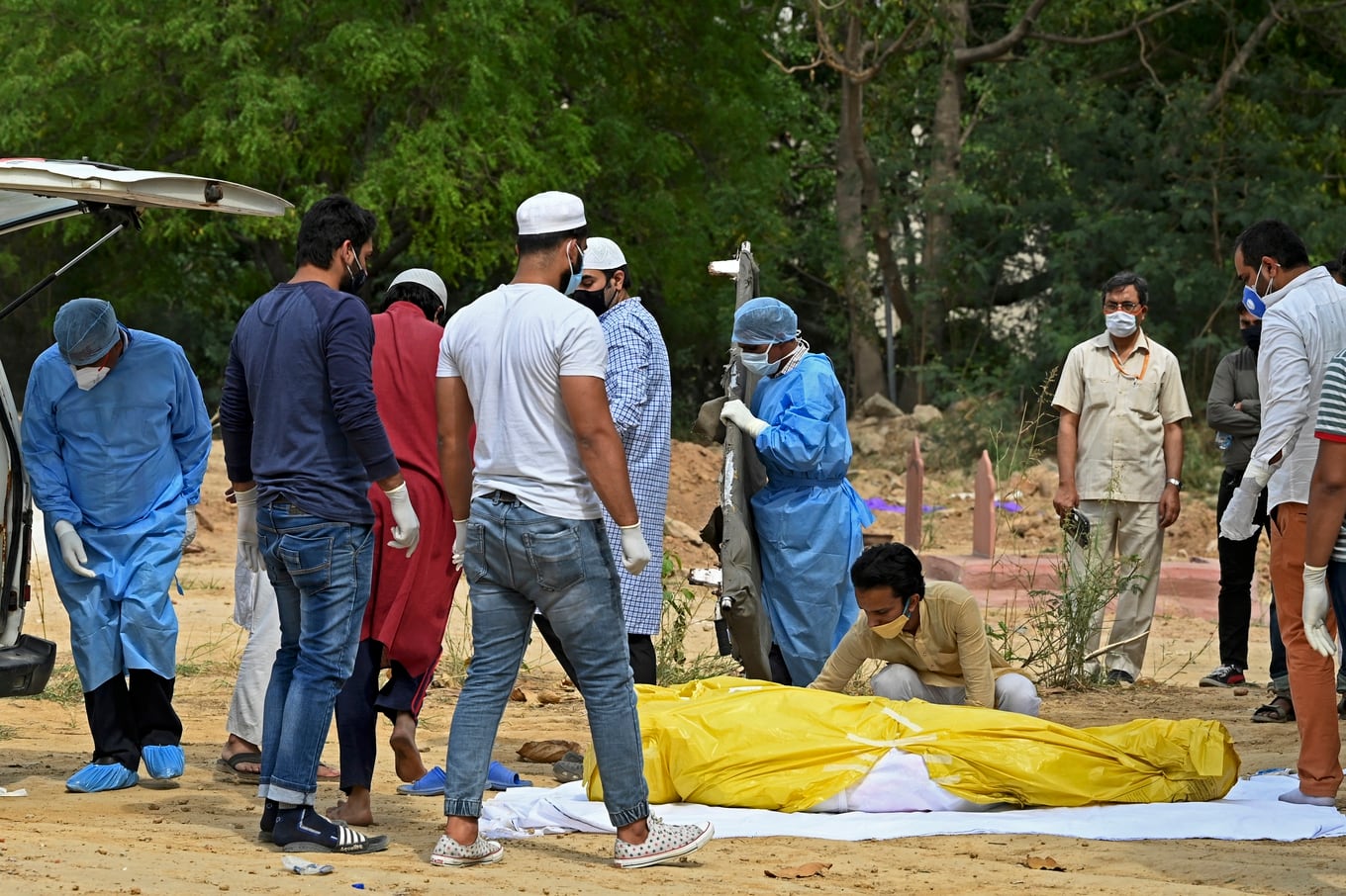 Relatives and friends stand next to the dead body of a Covid-19 coronavirus victim during the burial at a graveyard in New Delhi on April 5, 2021. (Photo by Sajjad HUSSAIN / AFP) / �The erroneous mention[s] appearing in the metadata of this photo by Sajjad HUSSAIN has been modified in AFP systems in the following manner: [April 5] instead of [April 3]. Please immediately remove the erroneous mention[s] from all your online services and delete it (them) from your servers. If you have been authorized by AFP to distribute it (them) to third parties, please ensure that the same actions are carried out by them. Failure to promptly comply with these instructions will entail liability on your part for any continued or post notification usage. Therefore we thank you very much for all your attention and prompt action. We are sorry for the inconvenience this notification may cause and remain at your disposal for any further information you may require.�