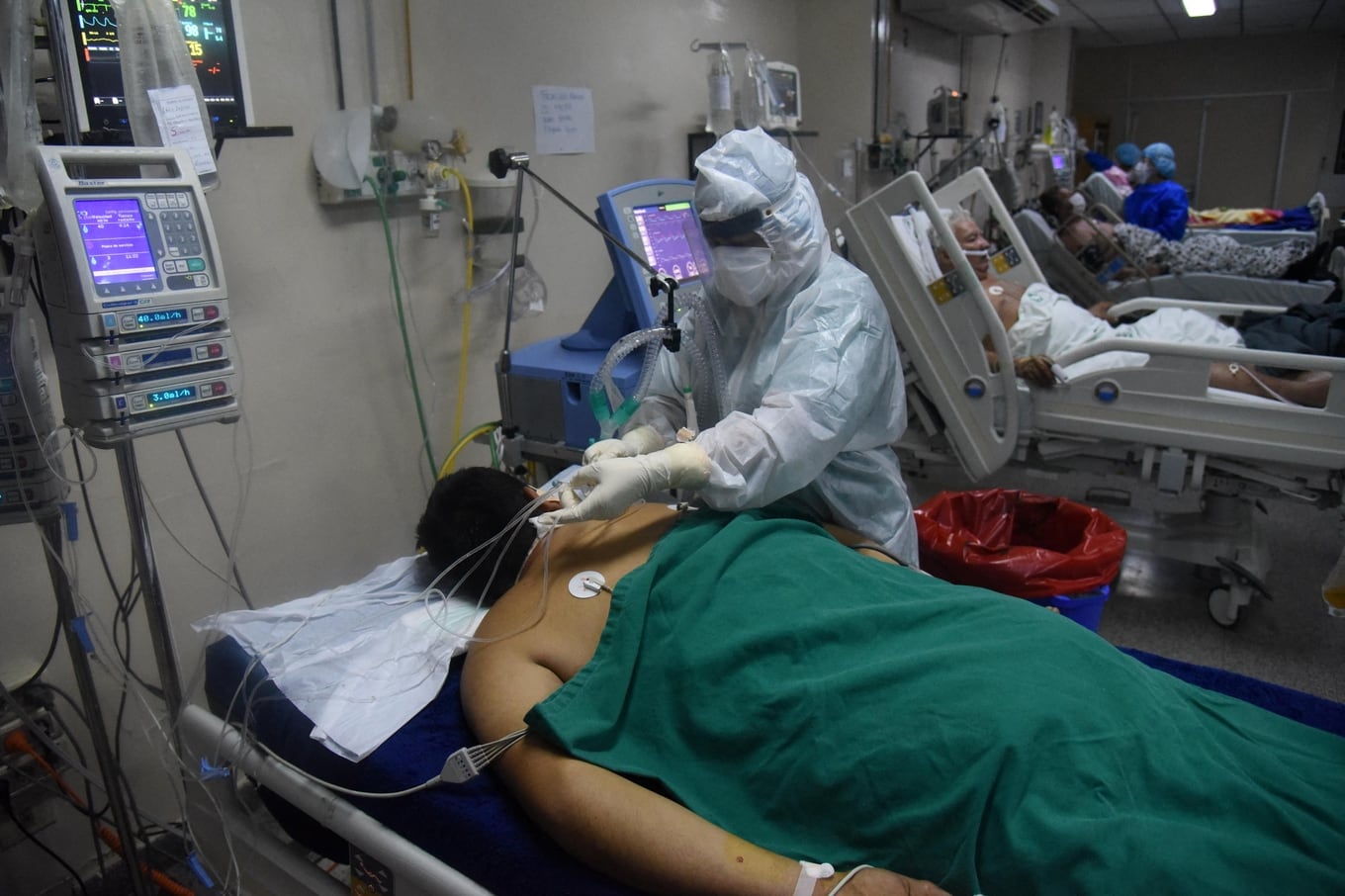 A health worker assists a COVID-19 patient at the intensive care unit of the Clinics Hospital in San Lorenzo, Paraguay, on March 16, 2021. - Paraguay's government reinforced restrictions due to an increase in the number of cases of COVID-19, which has collapsed the healthcare system. (Photo by DANIEL DUARTE / AFP)